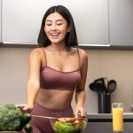 Slim Asian Woman In Fitwear Cooking Fresh Vegetable Salad For Dinner Standing In Kitchen Dieting At Home On Weekend. Detox Diet And Nutrition For Weight Loss, Healthy Food Recipes Concept