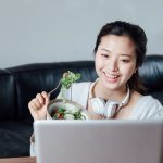 Young Asian woman eating salad after exercise